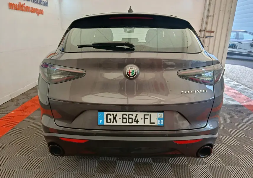 Vue arrière d'un Alfa Romeo Stelvio gris foncé avec feux LED et double sortie d'échappement intégrée.
