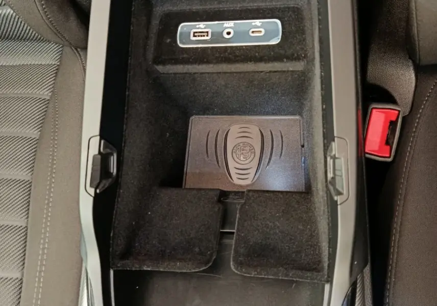 Vue plongeante sur la console centrale noire de l'Alfa Romeo Stelvio gris foncé, avec ports USB et tapis de recharge à induction.