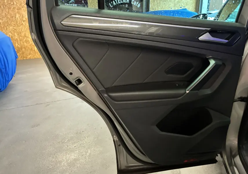 Vue intérieure de la porte arrière droite grise du Volkswagen Tiguan 2.0 TDI 150 Carat avec garniture noire et poignée argentée.