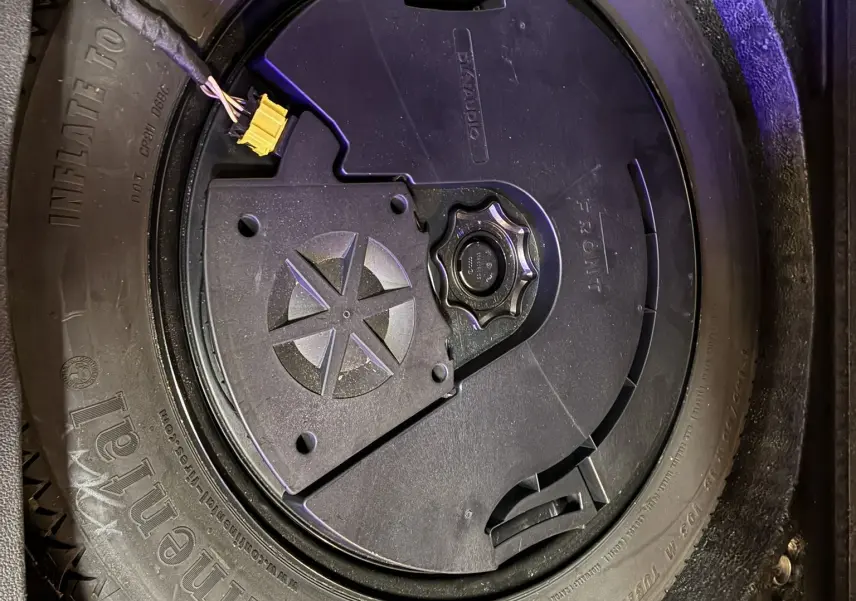 Gros plan sur la roue de secours noire dans le coffre d’un Volkswagen Tiguan gris 2017, avec outil de fixation visible.