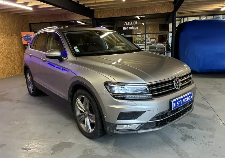 Volkswagen Tiguan gris 2017 en 3/4 avant droit dans un garage avec phares allumés et jantes alliage.