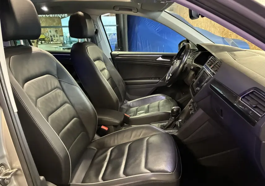 Vue intérieure côté conducteur du Volkswagen Tiguan gris 2017, avec sièges en cuir noir et tableau de bord moderne.