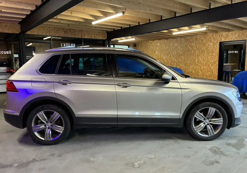 Vue de profil côté gauche d’un Volkswagen Tiguan gris 2017 avec jantes alliage 19 pouces dans un garage.