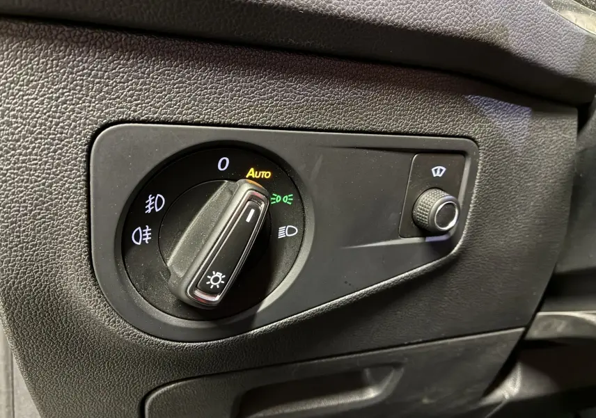 Gros plan sur le bouton de commande des phares du Volkswagen Tiguan 2.0 TDI 150 Carat, tableau de bord noir.
