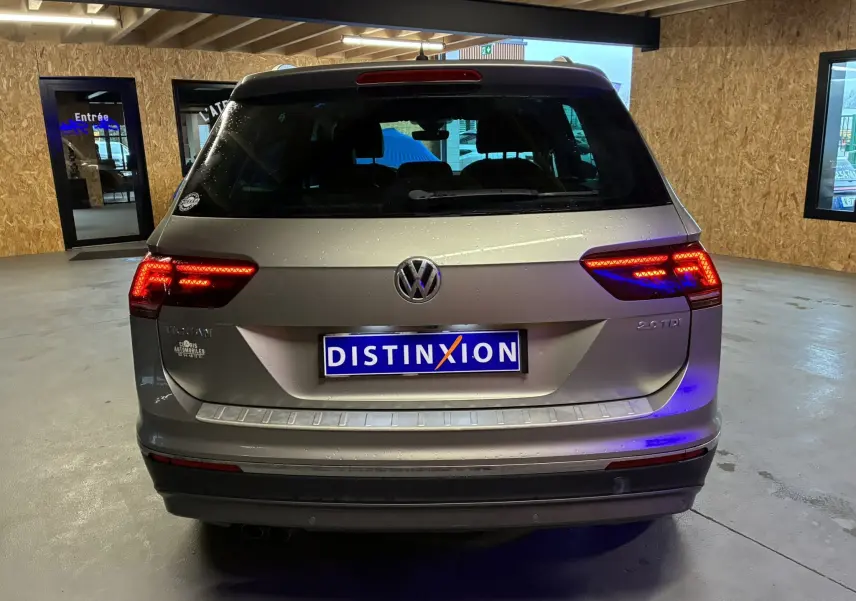 Vue arrière d’un Volkswagen Tiguan gris 2.0 TDI 150 Carat de 2017 avec feux allumés dans un garage intérieur.