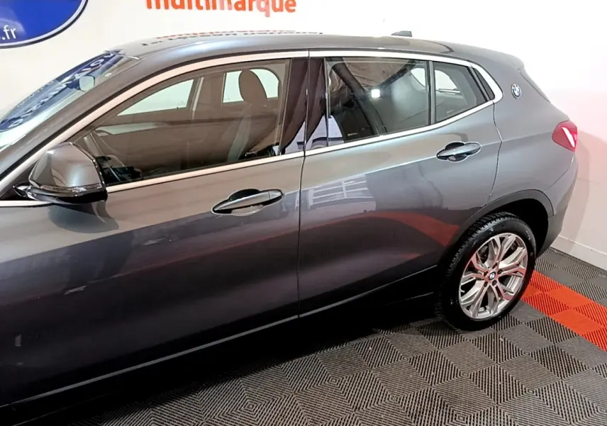 Vue latérale droite d'un BMW X2 gris foncé avec jantes alliage et rétroviseurs électriques rabattables.