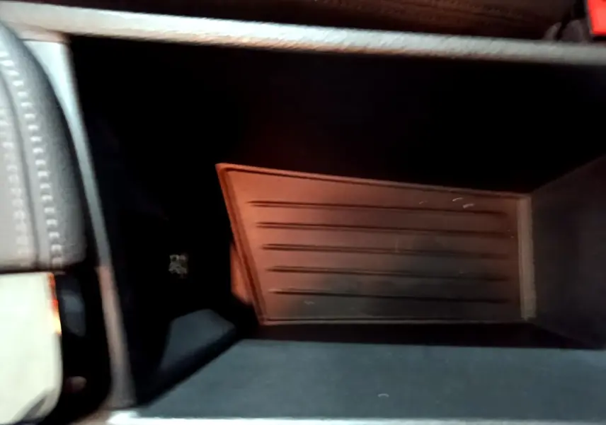 Intérieur du rangement central de la BMW X2 sDrive18i Lounge DKG7, vue plongeante sur le compartiment noir.