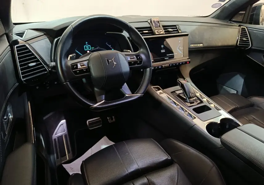 Vue intérieure côté conducteur du DS7 Crossback E-TENSE 4x4 2022, tableau de bord et volant cuir noir avec écran tactile central.