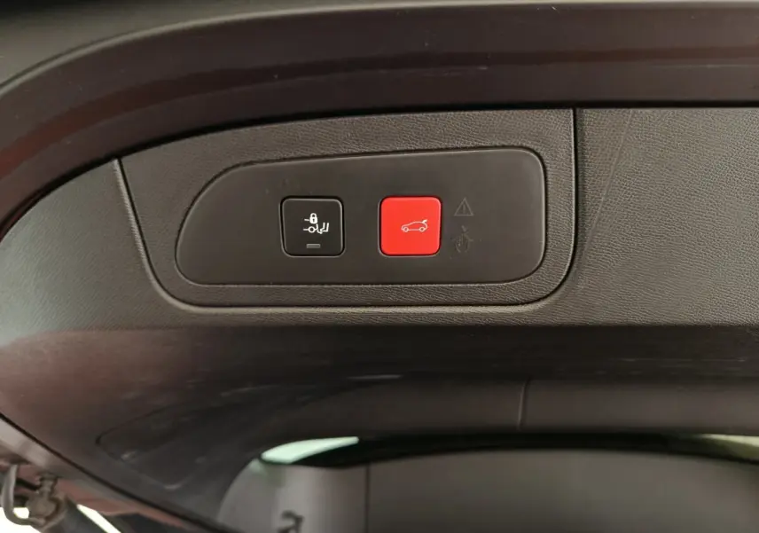 Gros plan sur les boutons de commande du hayon électrique noir et rouge à l'intérieur du coffre du DS7 Crossback noir.