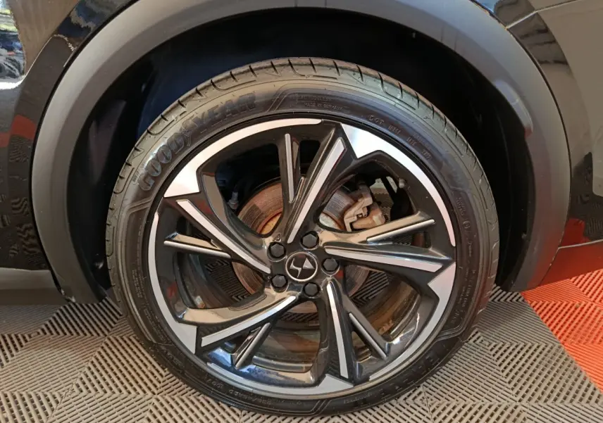 Gros plan sur la roue avant gauche noire du DS7 Crossback E-TENSE 4x4 300 Louvre avec jante alliage stylisée.