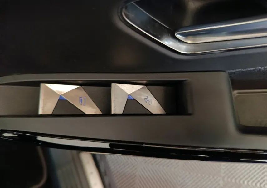Gros plan sur les commandes de lève-vitres en métal brossé à l'intérieur d'une DS7 Crossback noir.