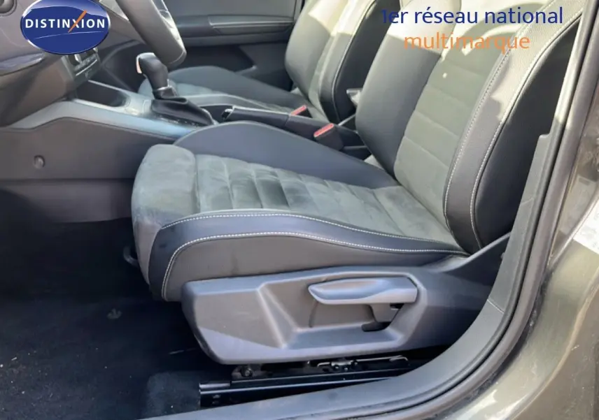 Vue intérieure côté conducteur du SEAT Arona 2025, sièges en tissu et cuir noir avec surpiqûres blanches.