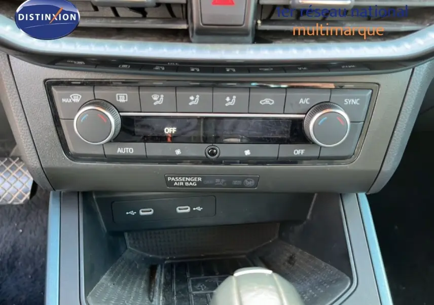 Gros plan sur la console centrale du SEAT Arona gris magnétique, montrant les commandes de climatisation et ports USB.