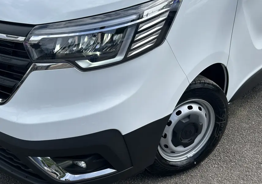 Gros plan sur l'avant droit blanc du Renault Trafic Fourgon avec phare LED et jante acier noire.