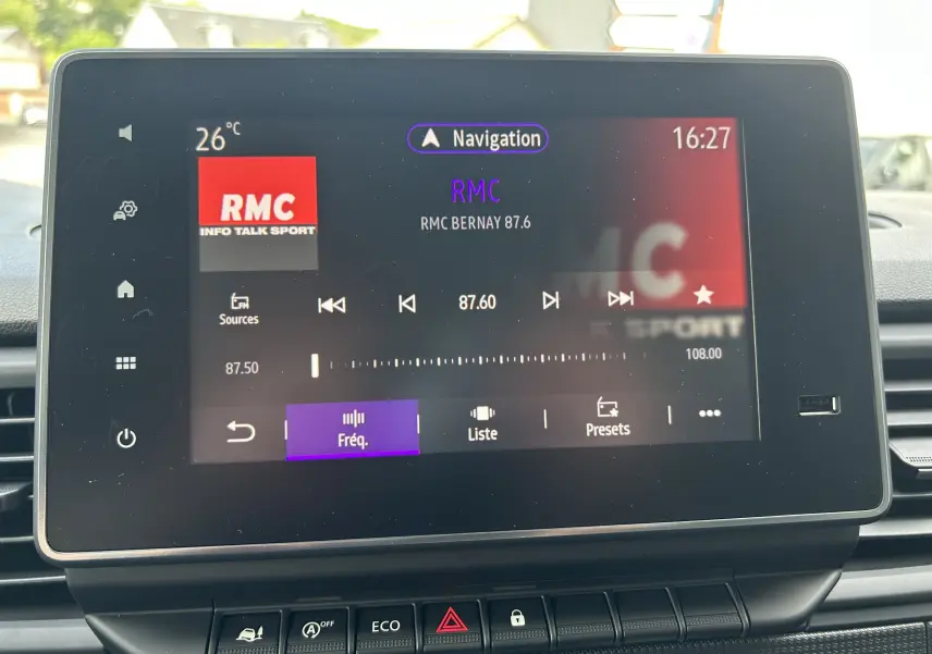 Écran tactile central du Renault Trafic blanc montrant la radio RMC à 87.6 FM avec commandes en bas.