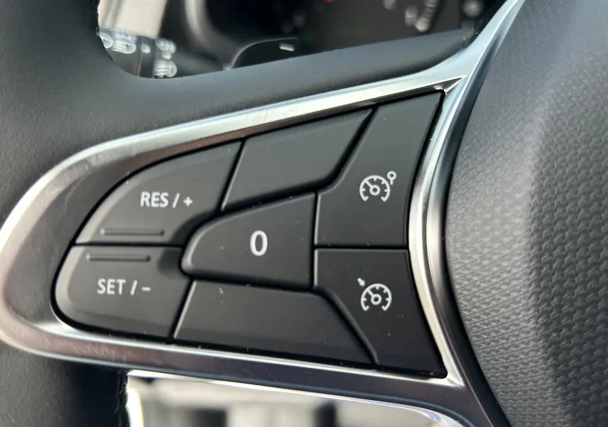 Gros plan sur les commandes de régulateur de vitesse au volant du Renault Trafic Fourgon blanc, version 2026.