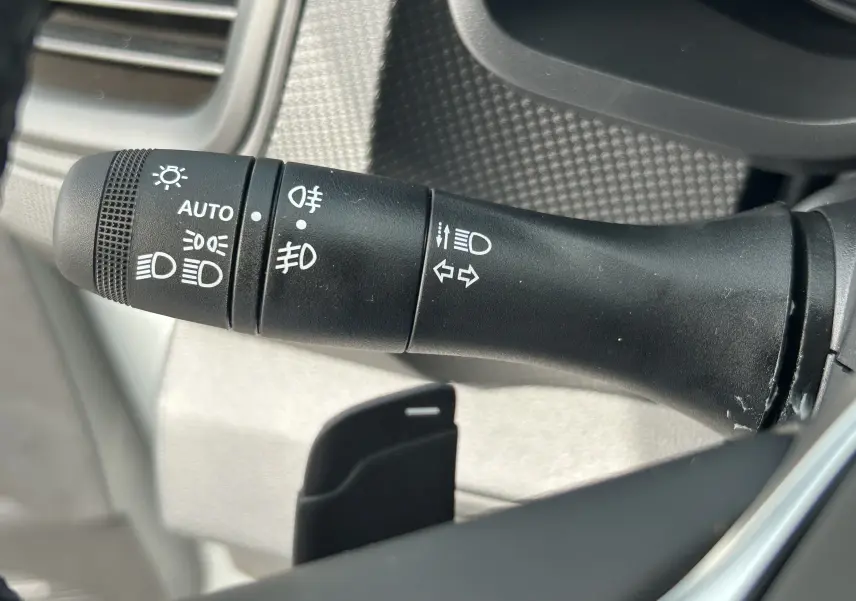 Gros plan sur la commande des feux et clignotants dans l'habitacle du Renault Trafic Fourgon blanc.