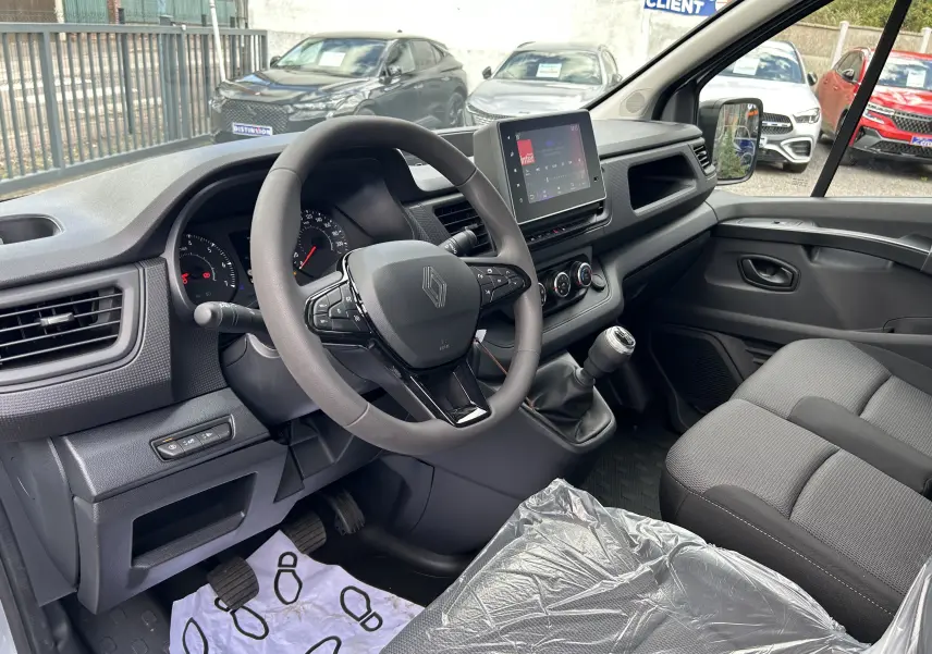 Vue intérieure côté conducteur du Renault Trafic blanc 2026, volant multifonction, tableau de bord et écran tactile visibles.