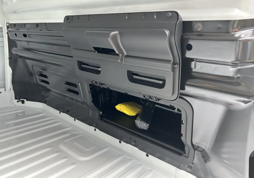 Détail intérieur de la cloison complète tôlée du Renault Trafic Fourgon blanc avec trappe de rangement ouverte.