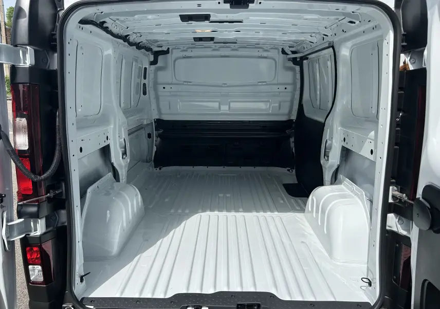 Vue arrière intérieure du fourgon blanc Renault Trafic L1H1 2026, montrant la grande zone de chargement vide et métallique.