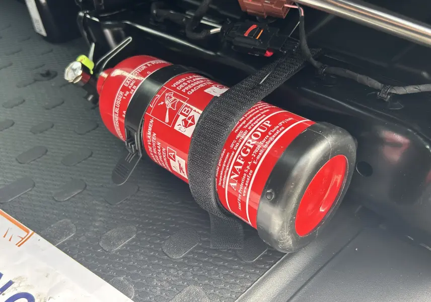 Gros plan sur l’extincteur rouge fixé dans le compartiment de chargement du Renault Trafic Fourgon blanc.