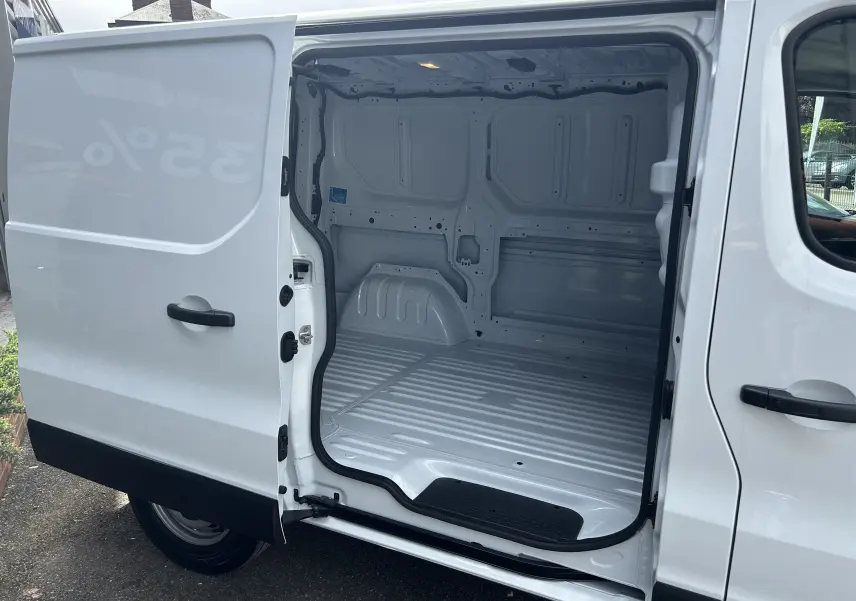 Vue latérale droite du Renault Trafic fourgon blanc avec porte coulissante ouverte montrant l’espace de chargement vide.