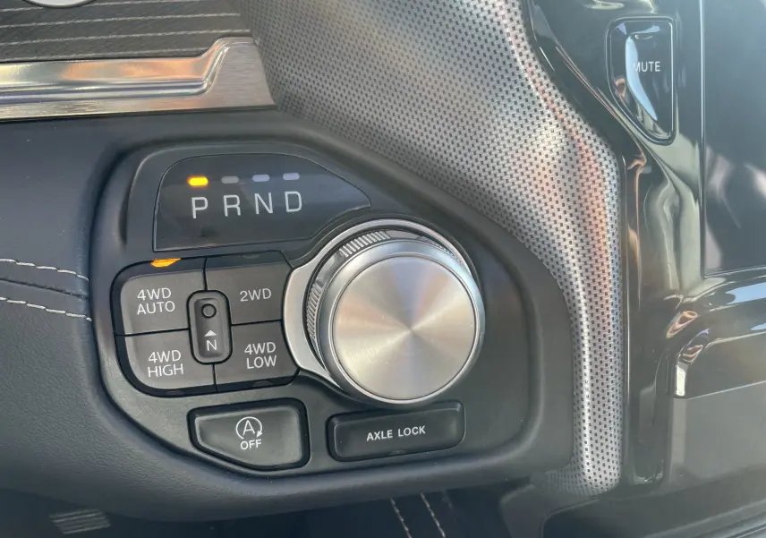 Gros plan sur la commande rotative de boîte automatique et sélecteur 4x4 du Dodge RAM 1500 blanc nacré, intérieur noir.