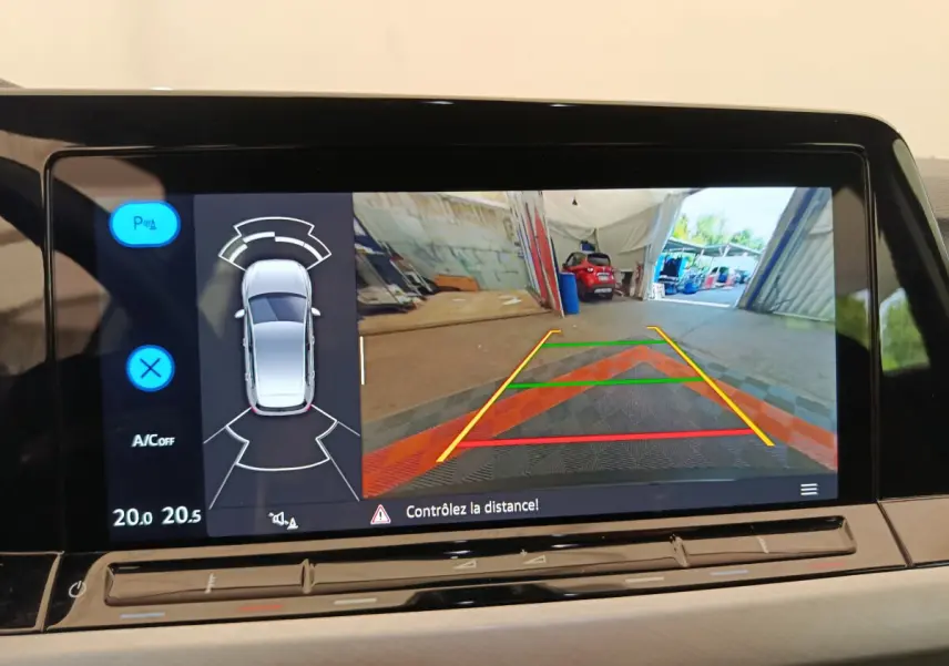 Écran tactile de la Volkswagen Golf gris foncé montrant la caméra de recul et les capteurs de stationnement arrière.