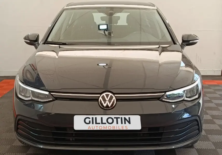 Vue frontale d'une Volkswagen Golf gris foncé avec phares LED et logo VW centré sur calandre noire.