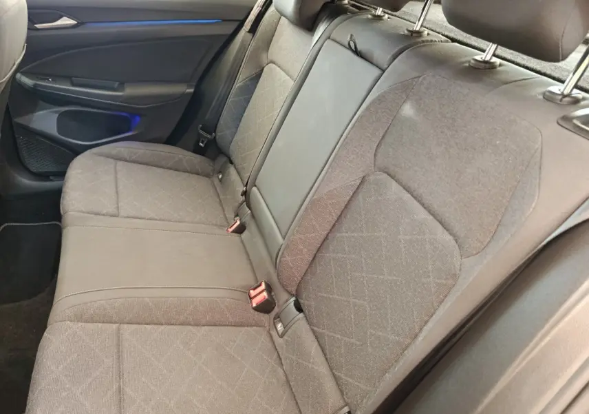 Banquette arrière grise vue côté droit dans une Volkswagen Golf 2022, avec éclairage d'ambiance bleu sur la portière.