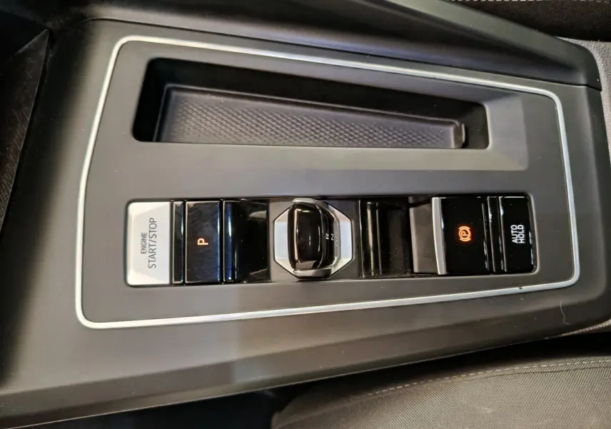 Gros plan sur la console centrale noire de la Volkswagen Golf 2022 avec levier de vitesses automatique et bouton start/stop.