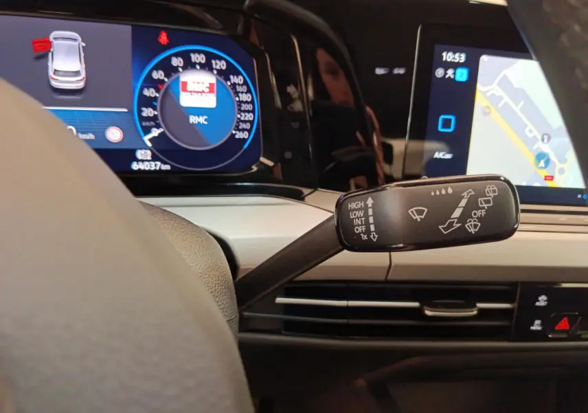 Gros plan sur le commodo d’essuie-glace dans l’habitacle gris clair d’une Volkswagen Golf 2022 avec tableau de bord numérique.