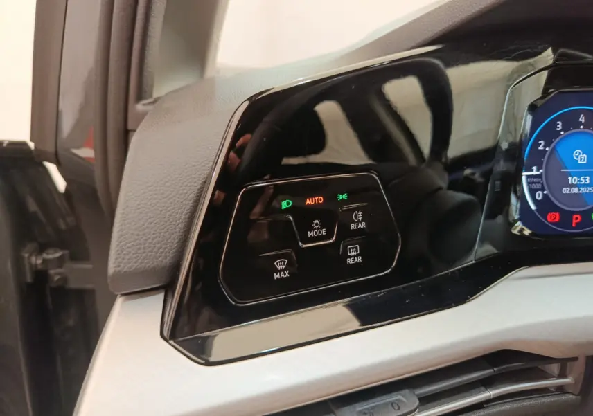 Détail du tableau de bord noir brillant côté gauche avec commandes d'éclairage et affichage digital bleu sur Volkswagen Golf gris foncé.