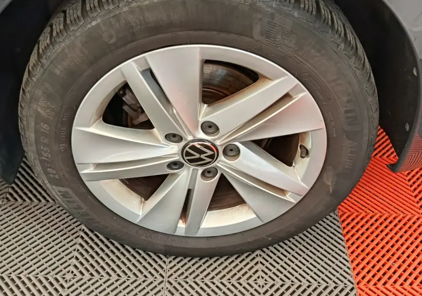 Gros plan sur la roue avant droite d'une Volkswagen Golf gris foncé avec jante alliage à cinq branches.