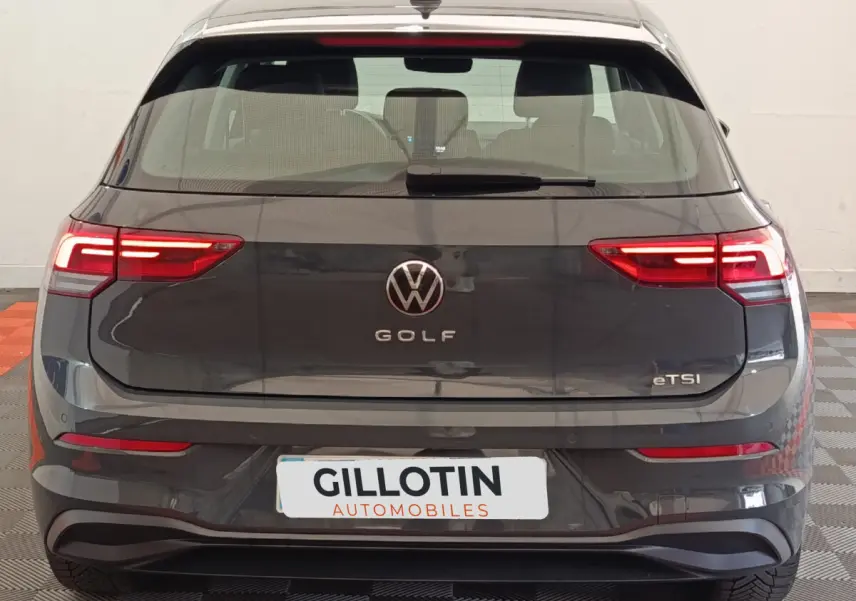 Vue arrière d'une Volkswagen Golf gris foncé avec feux LED allumés et logo central visible.