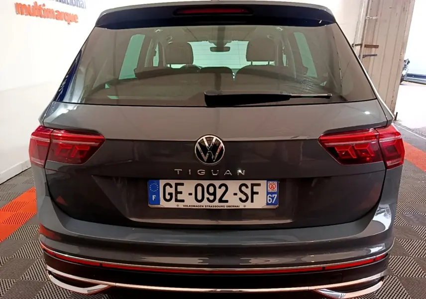 Vue arrière d’un Volkswagen Tiguan gris clair avec feux LED et plaque d’immatriculation française visible en intérieur.
