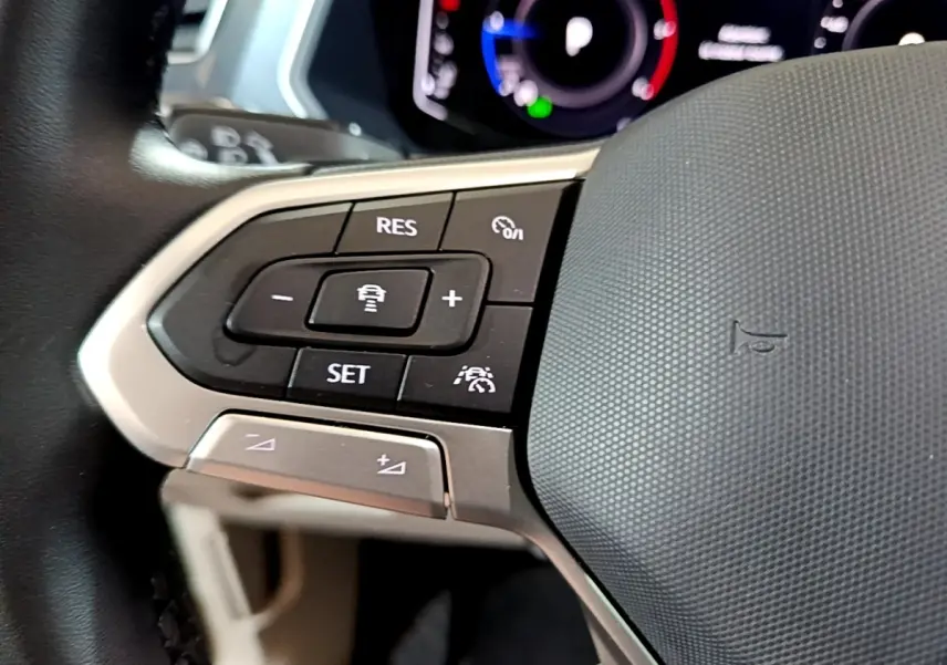 Gros plan sur les commandes de régulateur de vitesse au volant cuir du Volkswagen Tiguan gris clair 2022.