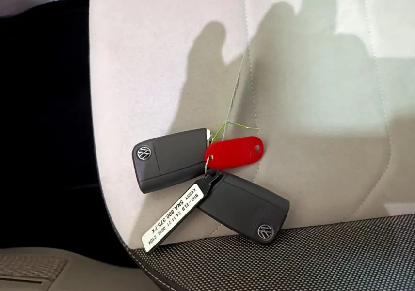 Clés Volkswagen noires posées sur siège clair avec tissu gris foncé, intérieur du Volkswagen Tiguan 2022.