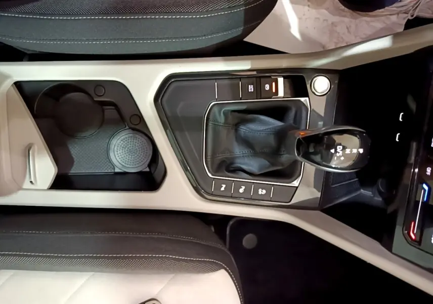 Vue plongeante sur la console centrale beige et noire du Volkswagen Tiguan 2022 avec levier de vitesse automatique et rangements.