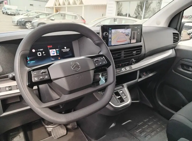 Vue intérieure côté conducteur du Citroën Jumpy Cabine Approfondie 2025, tableau de bord noir avec écran multimédia et volant multifonction.