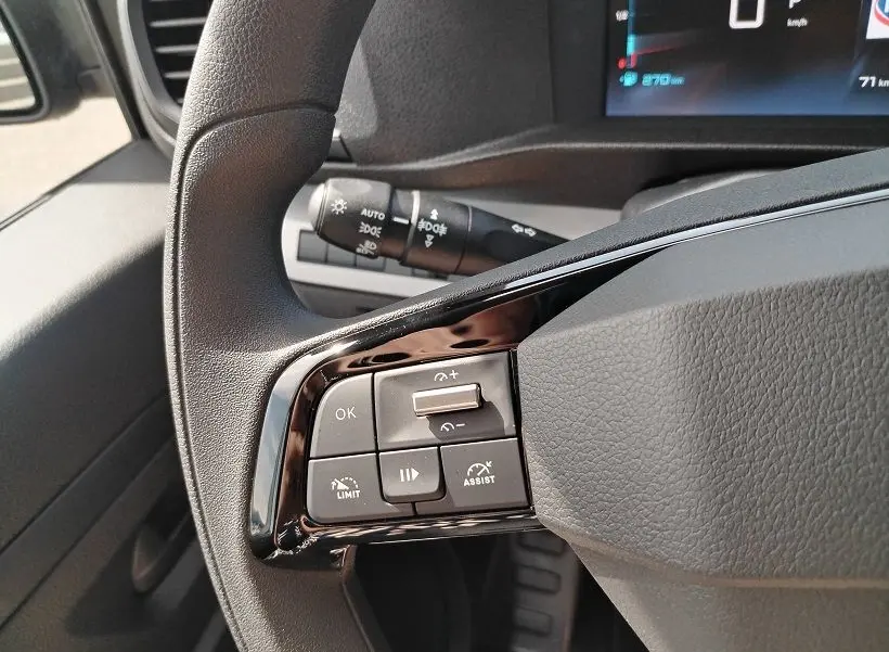 Gros plan sur les commandes gauche au volant du Citroën Jumpy Cabine Approfondie gris titane, avec tableau de bord numérique en arrière-plan.