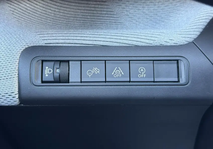 Gros plan sur les commandes de réglage des phares et d'assistance à la conduite dans une Citroën C3 Rouge Elixir.