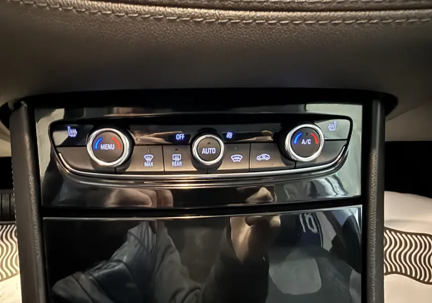 Gros plan sur la console centrale de l’Opel Grandland X blanc, montrant les commandes de climatisation et sièges chauffants.