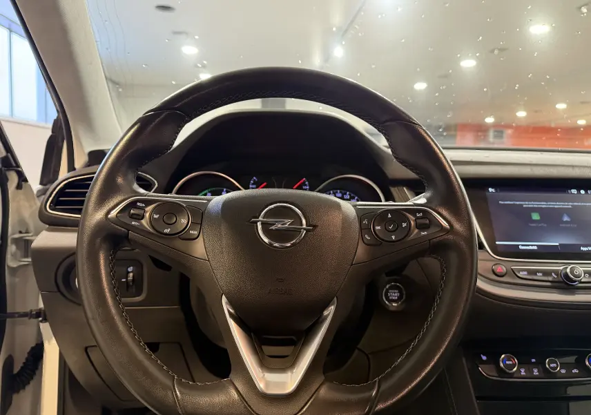 Vue intérieure centrée sur le volant noir de l’Opel Grandland X 1.6 Hybrid Turbo, avec tableau de bord et écran tactile visibles.