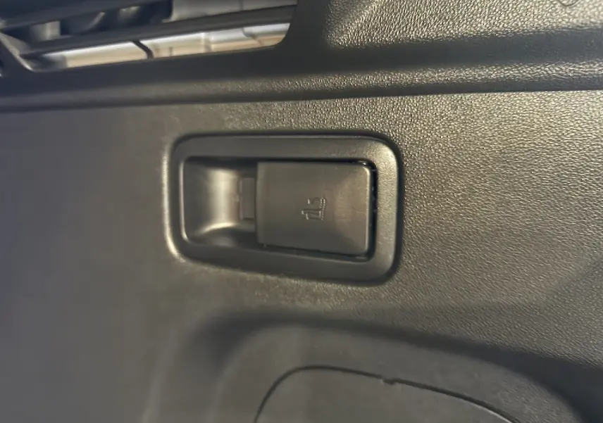 Gros plan sur la commande de rabattement des sièges arrière en plastique noir dans l'habitacle de l'Opel Grandland X blanc.