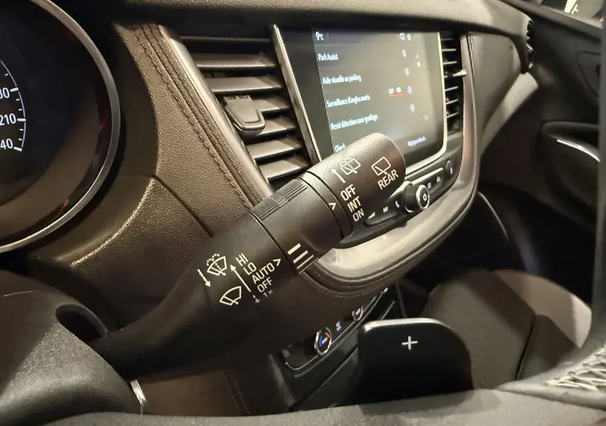 Gros plan sur la commande des essuie-glaces côté gauche du tableau de bord noir de l’Opel Grandland X blanc hybride.