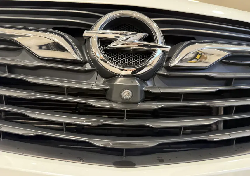 Gros plan sur la calandre noire et chromée avec le logo Opel en relief sur la face avant blanche du Grandland X.