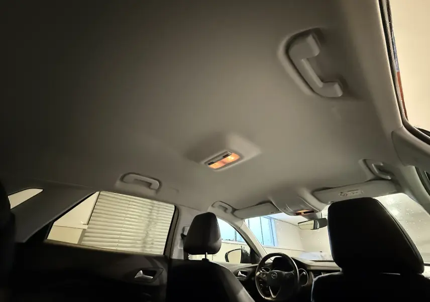 Vue intérieure du plafond et des sièges avant noirs de l'Opel Grandland X blanc, avec éclairage intérieur allumé.