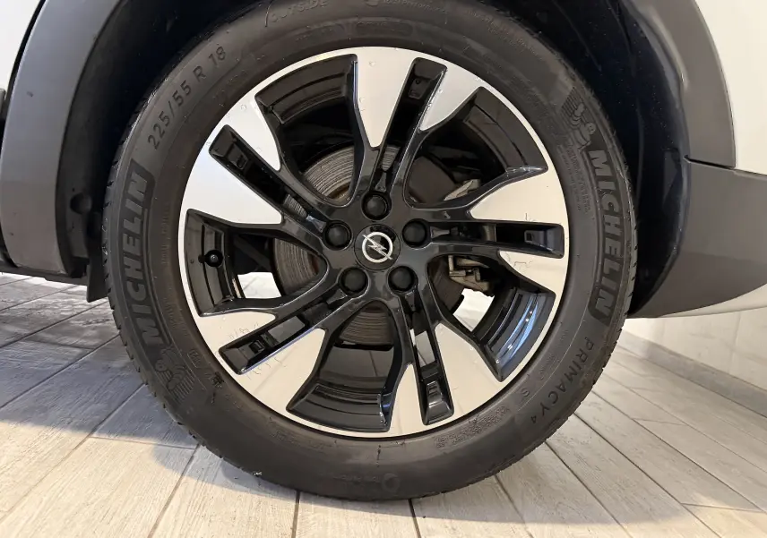 Gros plan sur la jante noire et argentée de 18 pouces avec logo Opel, montée sur un pneu Michelin d’un Grandland X blanc.