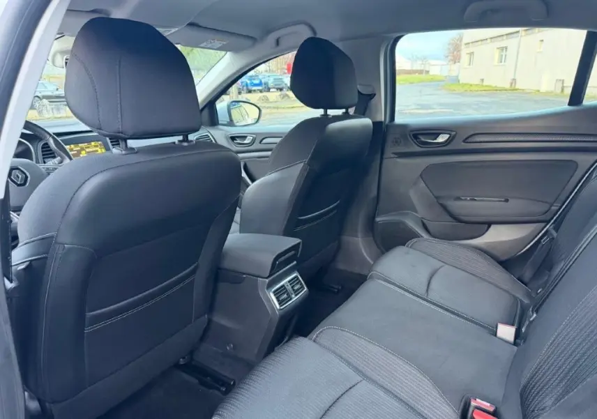 Vue intérieure arrière côté droit de la Renault Mégane Business gris alu, montrant les sièges et la console centrale avec aérateurs.